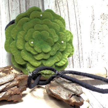 Runde grüne Umhängetasche aus Filz in Blumenform mit Perlenverzierung und Reißverschluss.