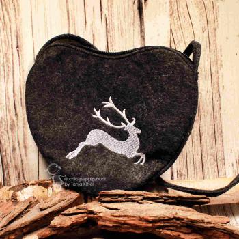 Dunkelgraue Filz-Umhängetasche in Herzform mit weißer Hirsch-Stickerei auf Holzgrund.