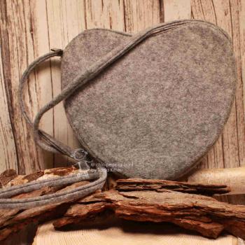 Rückseite der herzförmigen Filz-Handtasche in neutralem Hellgrau mit Schulterriemen.