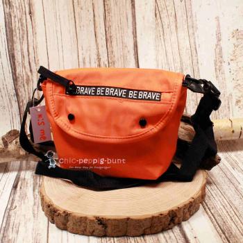 Kleine orangefarbene Umhängetasche aus Nylon mit weißem Be Brave Schriftzug auf der Vorderseite.