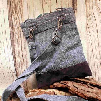 Rückseite der Stoff-Handtasche mit Fokus auf die silbernen Karabinerhaken des abnehmbaren Schulterbands.