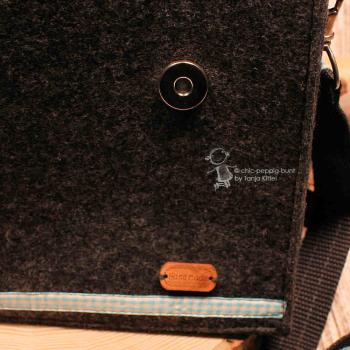 Nahaufnahme eines geschlossenen Magnetknopfs und des edlen Leder-Labels mit der Prägung Handmade.