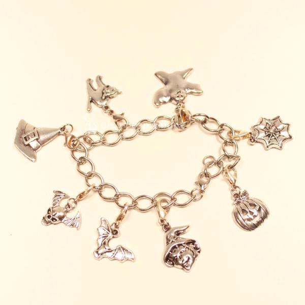 Versilbertes Bettelarmband mit großen Gliedern und 8 verschiedenen Halloween-Anhängern wie Kürbis, Hexe und Spinnweb.