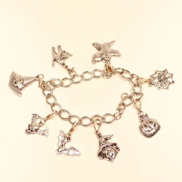 Versilbertes Bettelarmband mit großen Gliedern und 8 verschiedenen Halloween-Anhängern wie Kürbis, Hexe und Spinnweb.