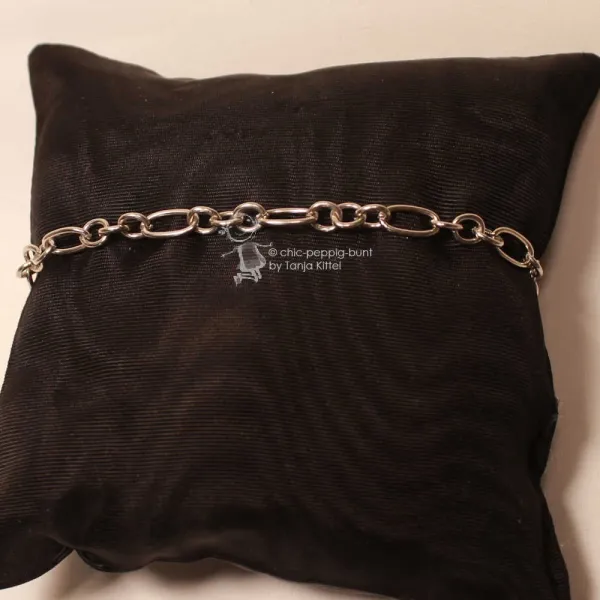 Versilbertes Gliederarmband mit Wechselmuster aus runden und rechteckigen Gliedern auf dunklem Schmuckkissen präsentiert.