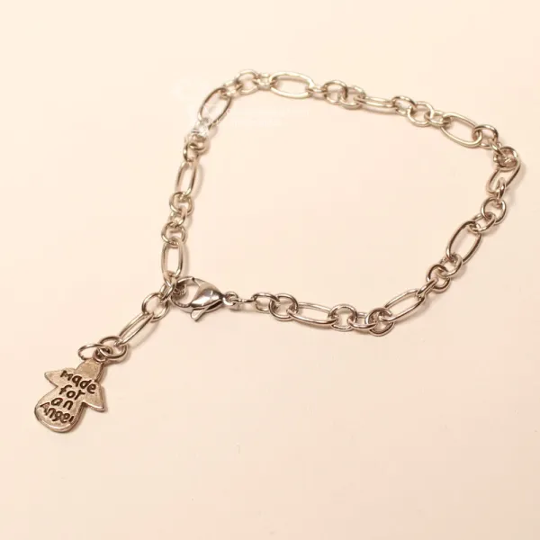 Ausgebreitetes versilbertes Metall-Armband mit Karabiner-Verschluss und Schutzengel-Charm auf hellem Untergrund.