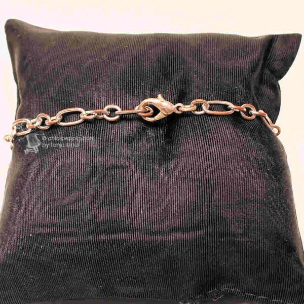 Versilbertes Gliederarmband mit geschlossenem Karabiner-Verschluss präsentieren auf einem schwarzen Schmuckkissen.