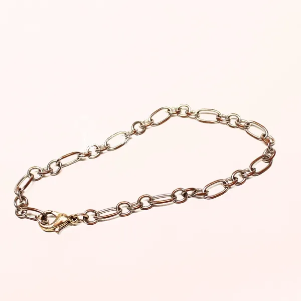 Ausgebreitetes versilbertes Bettelarmband aus Metall mit Wechselmuster aus runden und rechteckigen Gliedern sowie Karabiner-Verschluss.