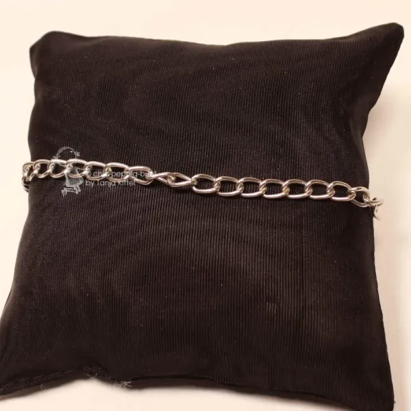 Versilbertes Aluminium-Gliederarmband mit großgliedriger Struktur auf einem schwarzen Schmuckkissen präsentiert.