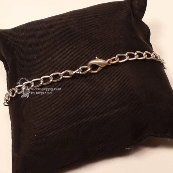 Nahaufnahme des geöffneten Karabiner-Verschlusses am leichtgliedrigen Metall-Aluminium-Armband auf schwarzem Kissen.
