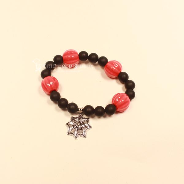 Elastisches Handmade Armband mit großen orange-schwarzen Kürbisperlen und silberfarbenem Spinnennetz-Anhänger.