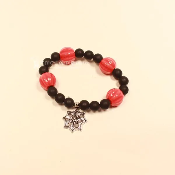 Elastisches Handmade Armband mit großen orange-schwarzen Kürbisperlen und silberfarbenem Spinnennetz-Anhänger.
