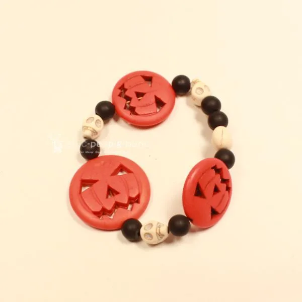 Elastisches Handmade Armband mit großen orangefarbenen Kürbisperlen und kleinen schwarzen Totenkopfperlen im Wechsel.