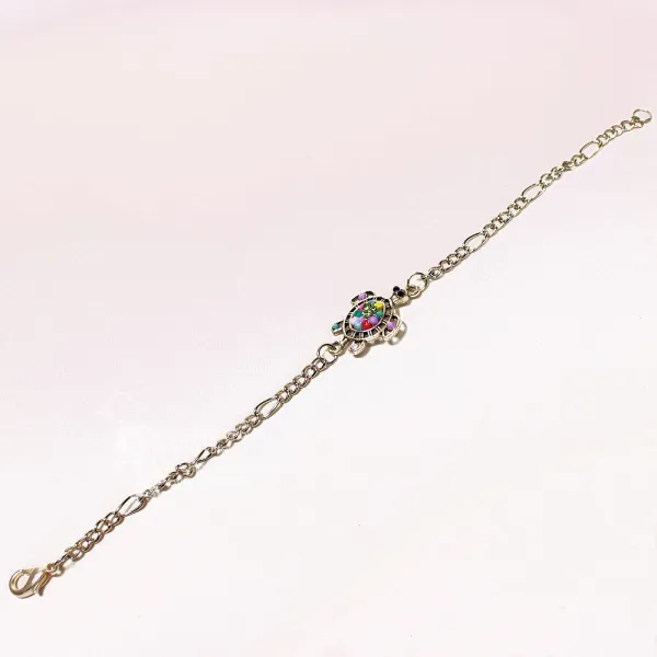 Ausgebreitetes versilbertes Bettelarmband aus Metall mit mittig platzierter Schildkröte und bunten Perlen auf hellem Untergrund.