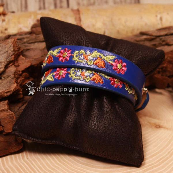 Nahaufnahme der farbenfrohen Blumen-Stickerei auf dem dunkelblauen Wickelarmband.