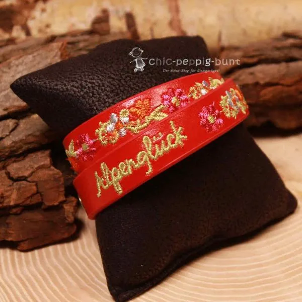 Nahaufnahme der hochwertigen Blumen-Stickerei auf dem roten Wickelarmband für Kinder.