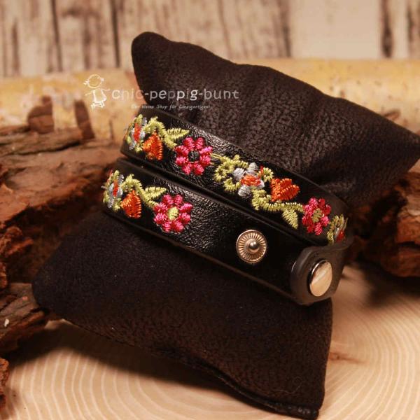 Nahaufnahme der hochwertigen Blumen-Stickerei auf dem schwarzen Wickelarmband für Kinder.