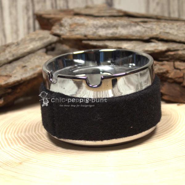 Nahaufnahme des schwarzem Aschenbechers und der feinen Stickerei des Hirsch-Motivs Nahaufnahme des schwarzem Aschenbechers und der feinen Stickerei des Hirsch-Motivs