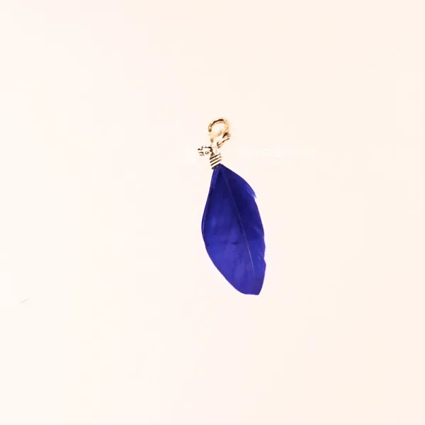 Handgemachter Charmsanhänger blaue Feder mit silberfarbenem Karabiner auf hellem Hintergrund.