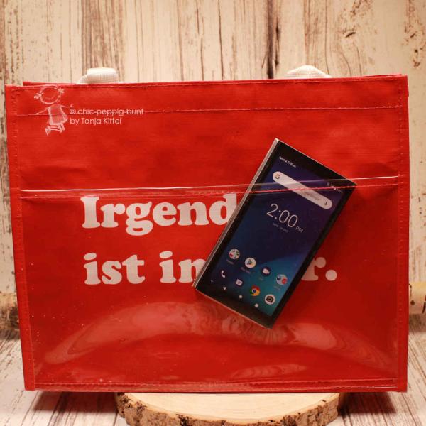 Nahaufnahme des Slogans „Irgendwas ist immer“ auf dem roten Polyester-Gewebe.
