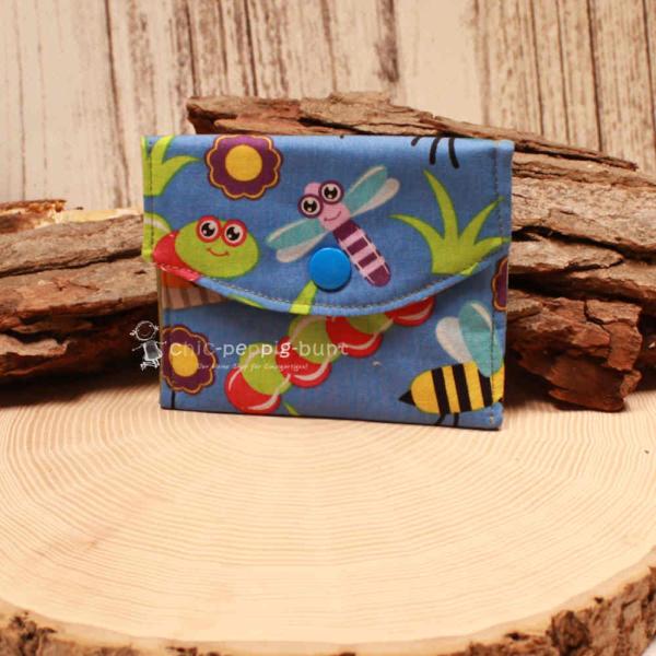 Kleiner handgenähter Geldbeutel von chic-peppig-bunt aus blauem Stoff mit Bienen-Motiv und grün gepunktetem Innenfutter auf hellem Hintergrund.