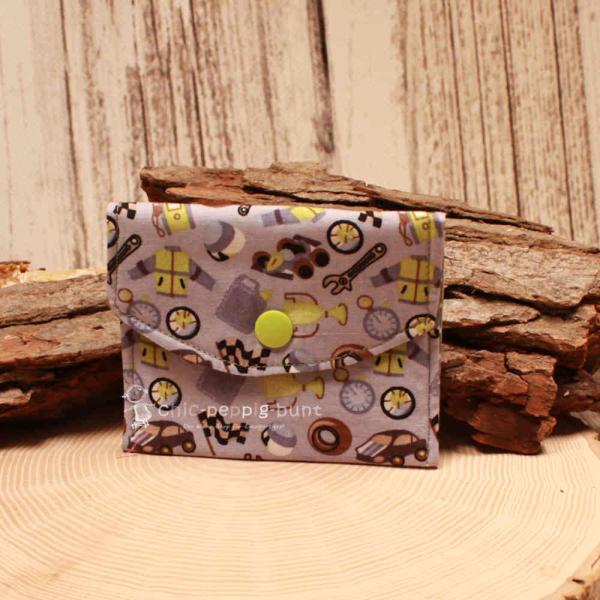 Kleiner handgenähter Geldbeutel von chic-peppig-bunt aus grauem Stoff mit Rennautos und Werkzeug sowie grünem Punkt-Futter auf hellem Hintergrund.