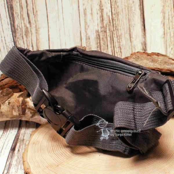 Rückseite der dunkelgrauen Hüfttasche mit Fokus auf das Reißverschlussfach hinten und die robuste Gurtschnalle mit Steckverschluss.