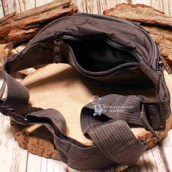 Detailaufnahme der geöffneten Fächer des dunkelgrauen Bauchbeutels zur Veranschaulichung des grauen Reißverschluss-Systems.