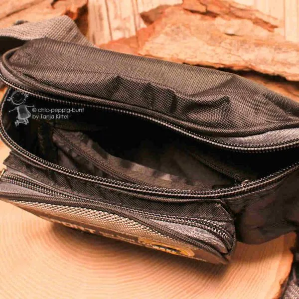 Nahaufnahme des geöffneten vorderen Fachs der Bumbag zur Demonstration des doppelten Reißverschluss-Systems.