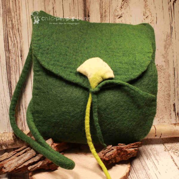 Flache grüne Handtasche aus Filz mit aufgenähter weißer Calla-Blüte, schwarzem Innenfutter und langem Schulterband vor neutralem Hintergrund.