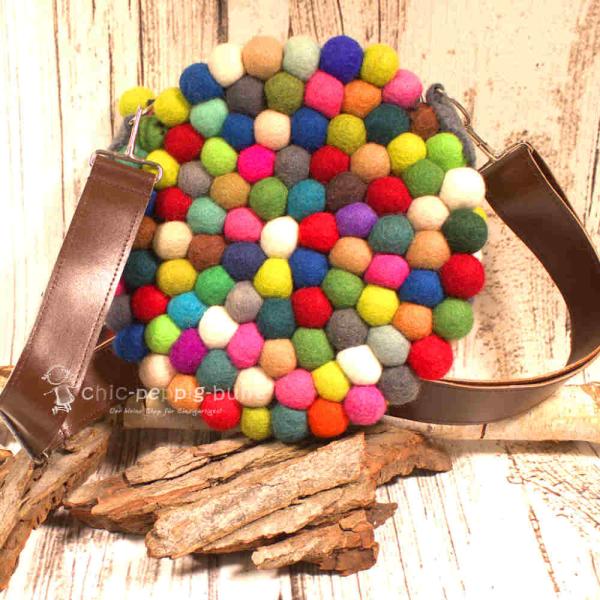 Die runde Filzkugel Handtasche hängt lässig am Lederriemen. Die runde Filzkugel Handtasche hängt lässig am Lederriemen.
