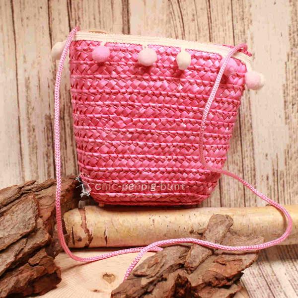 Kleine runde Korbtasche für Kinder in Rosa aus Rattan mit rosa Bommeln und Stoff-Innenfutter.