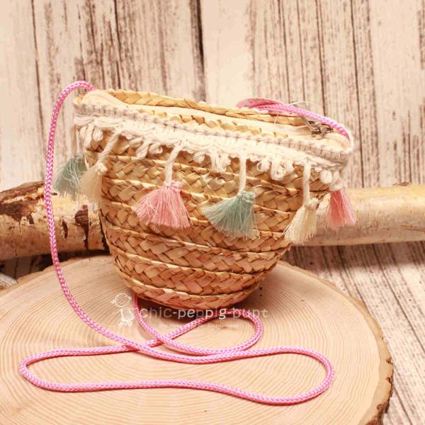 Kleine runde Korbtasche für Kinder aus naturfarbenem Rattan mit bunten Pastell-Quasten und Kordel-Schulterband.