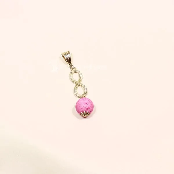 Versilberter Kettenanhänger mit einer runden rosa Korkperle und einem funkelnden, mit Strass besetzten Unendlichkeitszeichen.