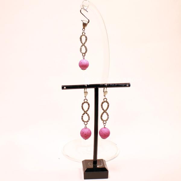 Versilbertes Schmuckset bestehend aus einem Kettenanhänger und passenden Ohrringen mit rosa Korkperlen und funkelndem Strass-Unendlichkeitszeichen.