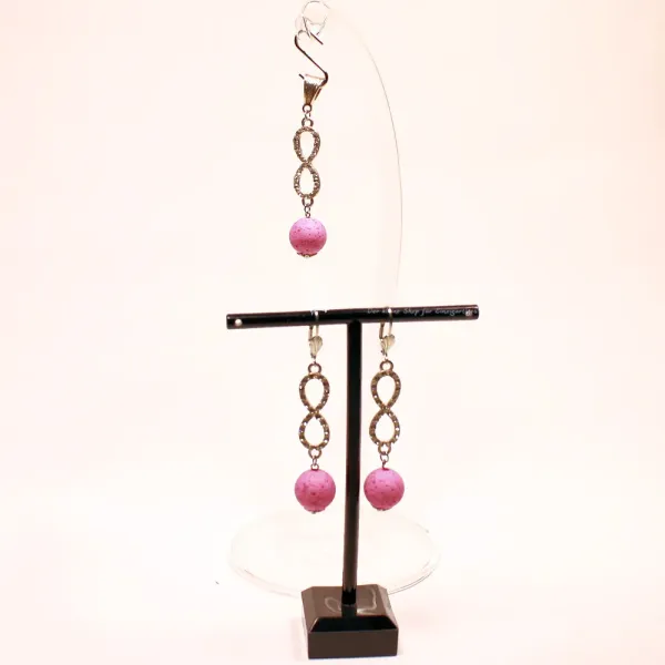 Versilbertes Schmuckset bestehend aus einem Kettenanhänger und passenden Ohrringen mit rosa Korkperlen und funkelndem Strass-Unendlichkeitszeichen.