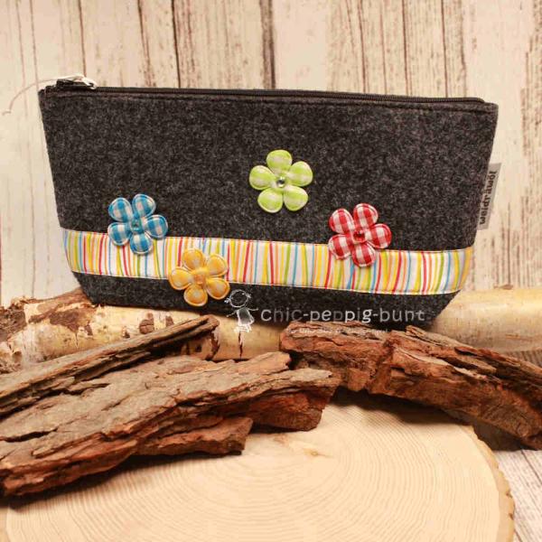 Handgenähte weidräwöl Kosmetiktasche aus grauem Filz mit lila Karoband und Blumen.