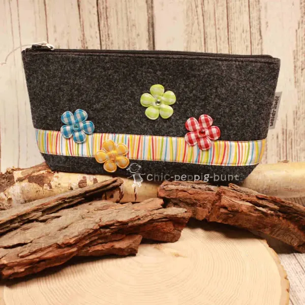 Handgenähte weidräwöl Kosmetiktasche aus grauem Filz mit lila Karoband und Blumen.