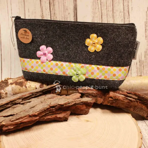 Handgenähte weidräwöl Kosmetiktasche aus grauem Filz mit bunten Punkten und Blumen.