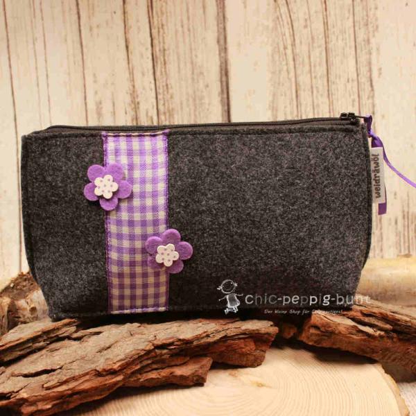 Handgenähte dunkelgraue Filz Kosmetiktasche mit lila Karoband und Blumen-Applikationen.