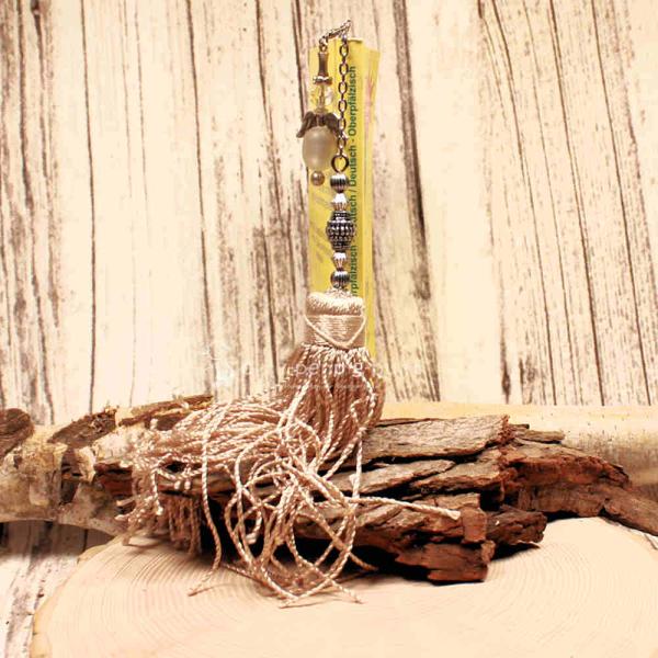 Langes Metall-Lesezeichen mit Ornamenten und großer Textilquaste in Beige.