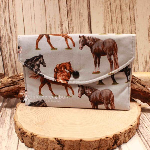 Großer handgenähter Geldbeutel von chic-peppig-bunt aus hellblauem Stoff mit Pferden und grau gepunktetem Innenfutter auf hellem Hintergrund.