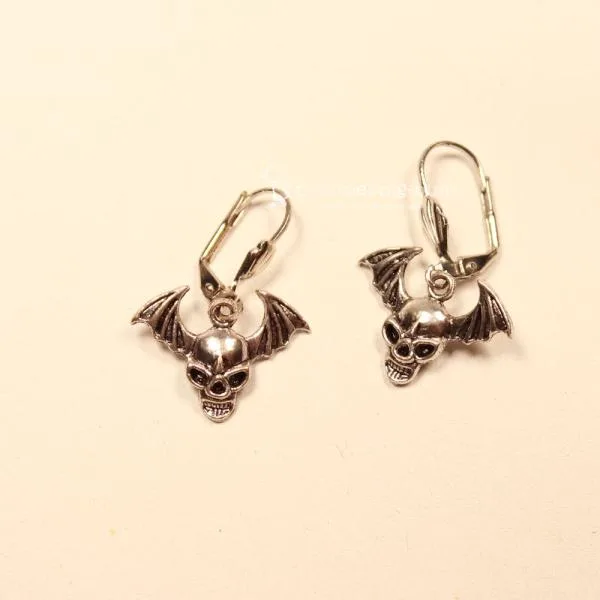 Handgefertigte silberfarbene Ohrringe mit Fledermaus- und Totenkopf-Motiv sowie versilberter Klappbrisur für Halloween.