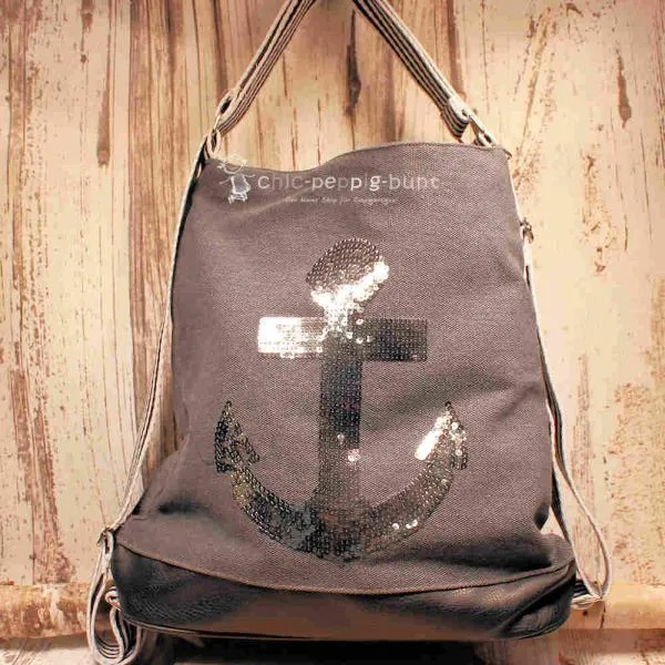 Grauer Rucksack aus Stoff mit silbernem Anker aus Pailletten, braunem Lederboden und gestreiften Gurten, 3-in-1 Funktion als Handtasche.
