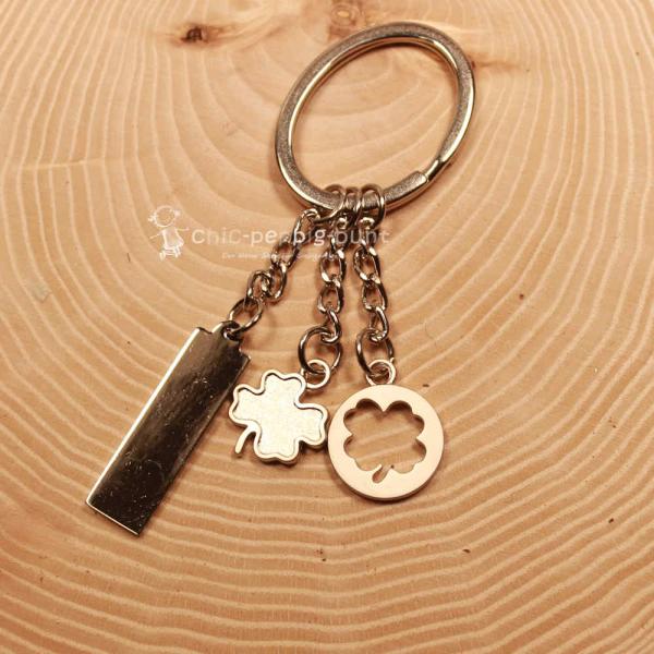 Versilberter Kleeblatt Schlüsselanhänger mit Gliederkette und drei Anhängern aus Metall.