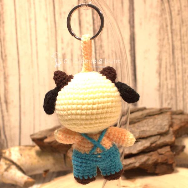 Nahaufnahme des gehäkelten Kuh-Taschenbaumlers aus Wolle. Gesamthöhe 16 cm, World Fair Trade, Hellblau. Nahaufnahme des gehäkelten Kuh-Taschenbaumlers aus Wolle. Gesamthöhe 16 cm, World Fair Trade, Hellblau.