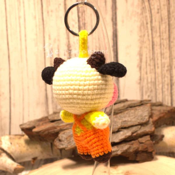 Nahaufnahme des gehäkelten Kuh-Taschenbaumlers aus Wolle. Gesamthöhe 16 cm, World Fair Trade, Orange. Nahaufnahme des gehäkelten Kuh-Taschenbaumlers aus Wolle. Gesamthöhe 16 cm, World Fair Trade, Orange.