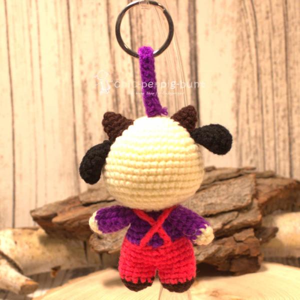 Nahaufnahme des gehäkelten Kuh-Taschenbaumlers aus Wolle. Gesamthöhe 16 cm, World Fair Trade, Rot. Nahaufnahme des gehäkelten Kuh-Taschenbaumlers aus Wolle. Gesamthöhe 16 cm, World Fair Trade, Rot.
