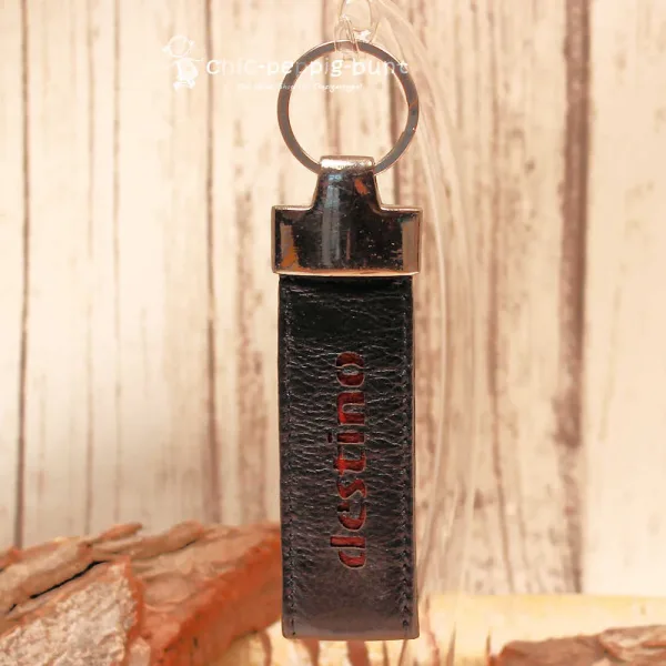 Detailaufnahme des 3 cm breiten Taschenanhängers aus Leder mit rotem Schriftzug destino.