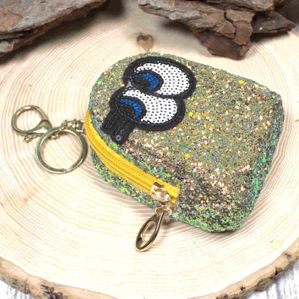 Gelbes Glitzer-Schlüsselmäppchen mit Augen-Motiv, geschlossen, frontal. Gelbes Glitzer-Schlüsselmäppchen mit Augen-Motiv, geschlossen, frontal.